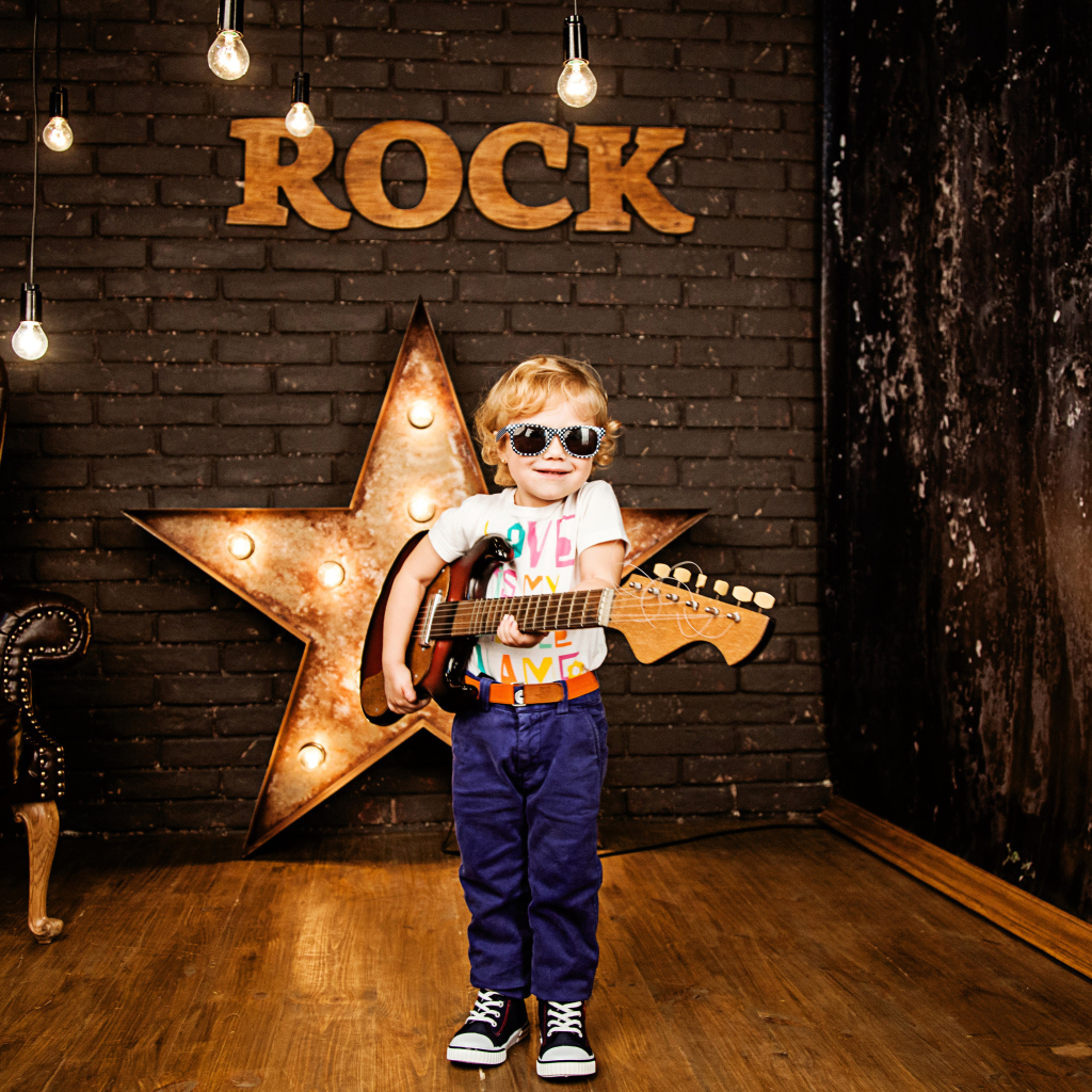 Маленький мальчик в модных очках с гитарой