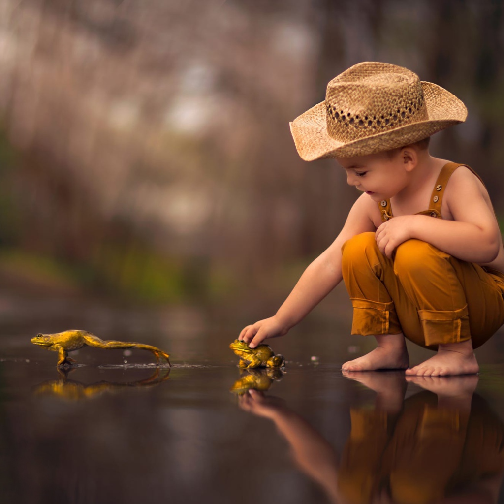 Маленький мальчик играет с лягушками 