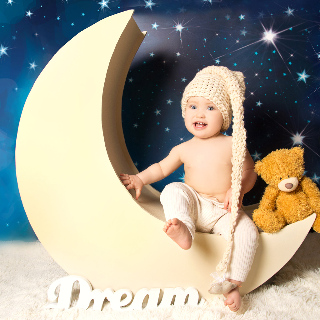 Маленький мальчик с плюшевым мишкой сидят на месяце