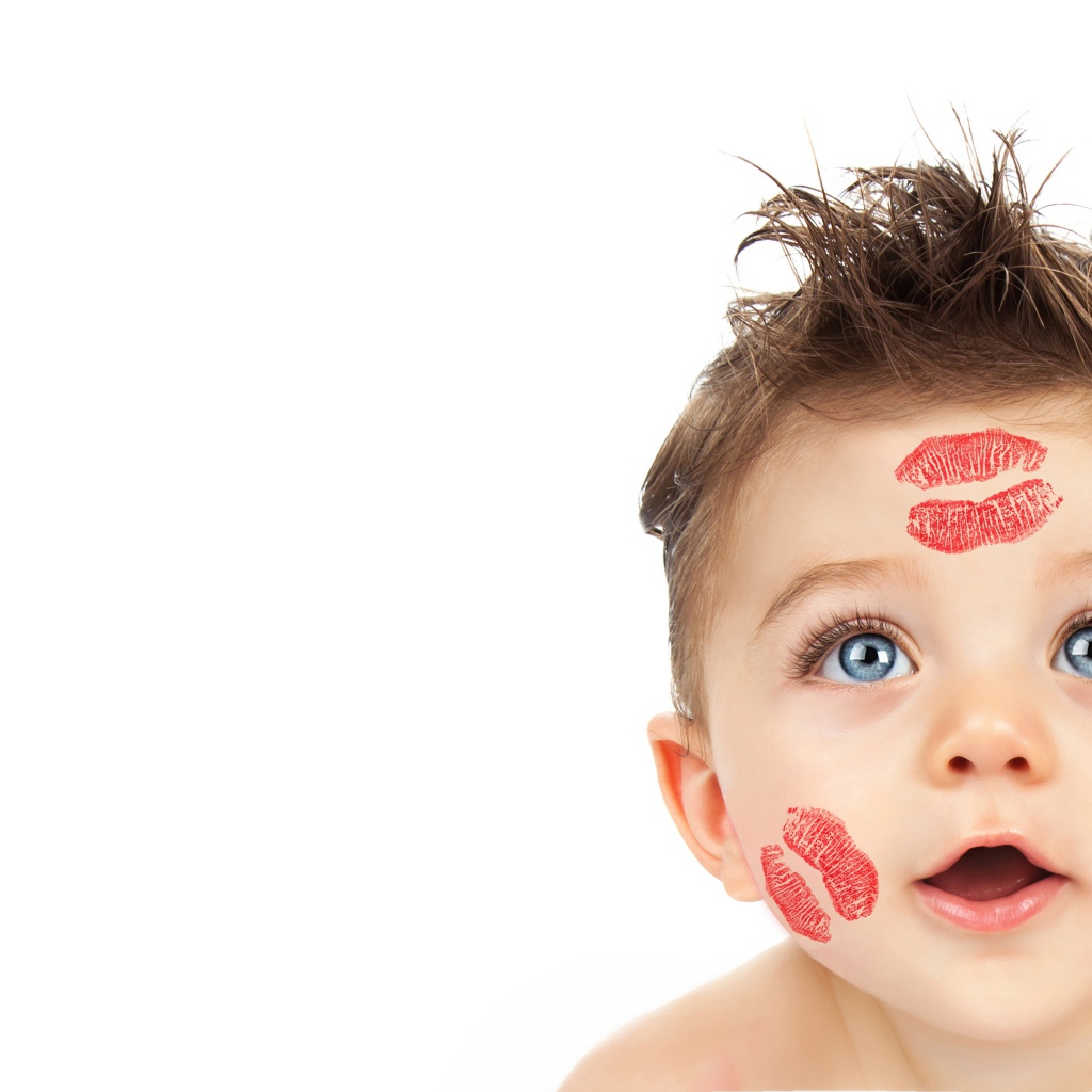 Маленький мальчик со следами от поцелуев на лице на белом фоне