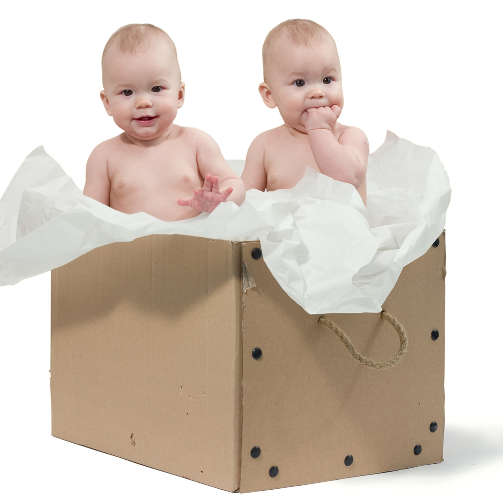 Маленькие дети сидят в картонной коробке с бумагой