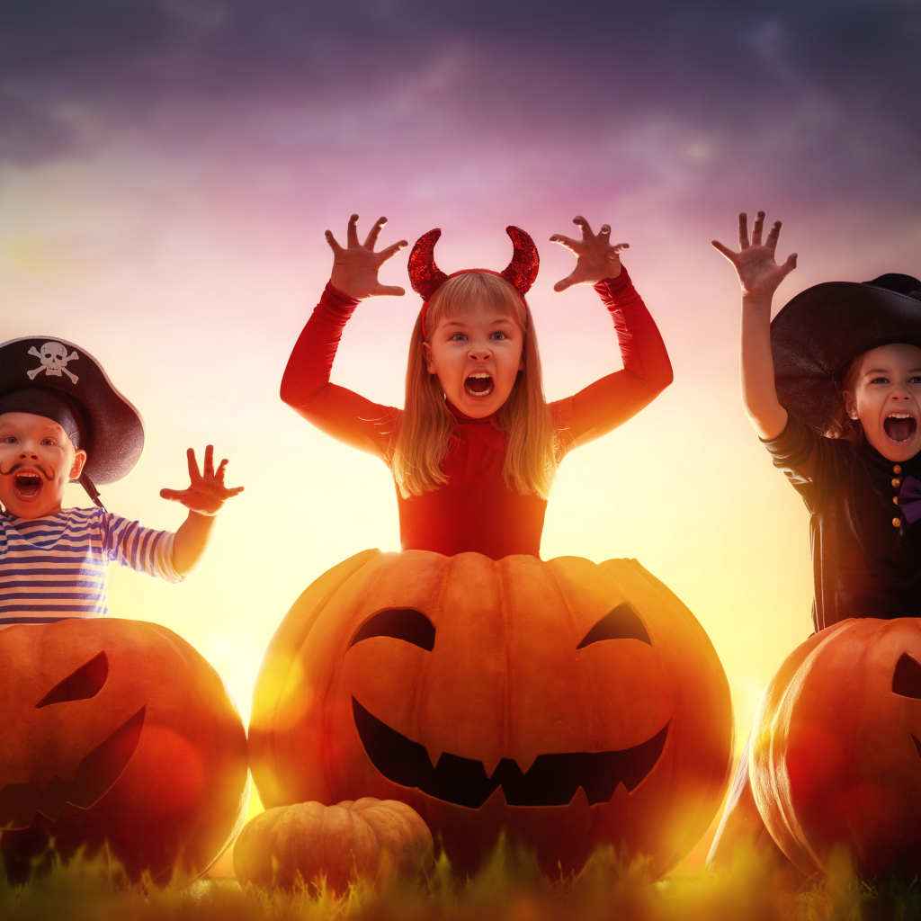Маленькие дети в костюмах на Хэллоуин с большими тыквами