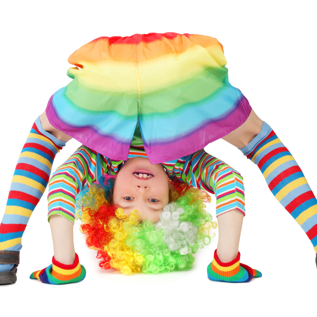 Маленькая смешная девочка в костюме клоуна на белом фоне