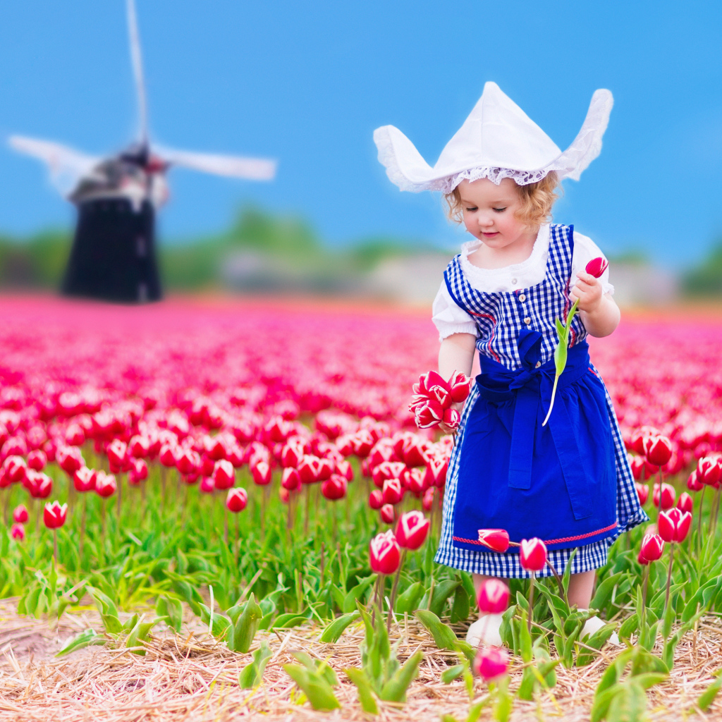 Маленькая девочка в голубом платье на поле тюльпанов 