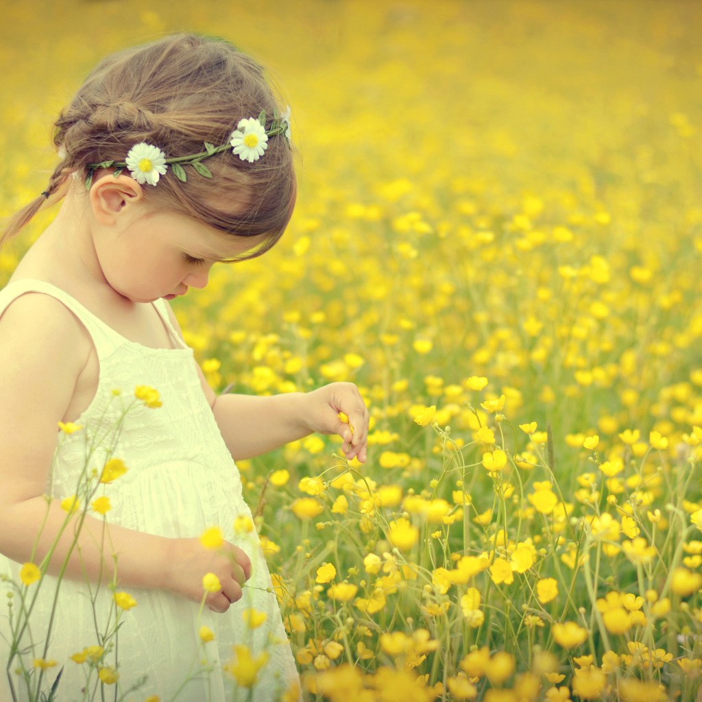Маленькая девочка в белом платье на лугу с желтыми цветами