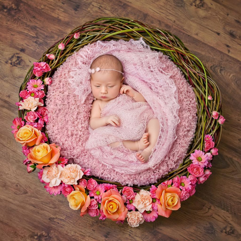 Маленькая девочка спит в корзине украшенной цветами