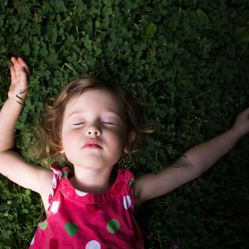 Маленькая девочка спит на зеленой траве 