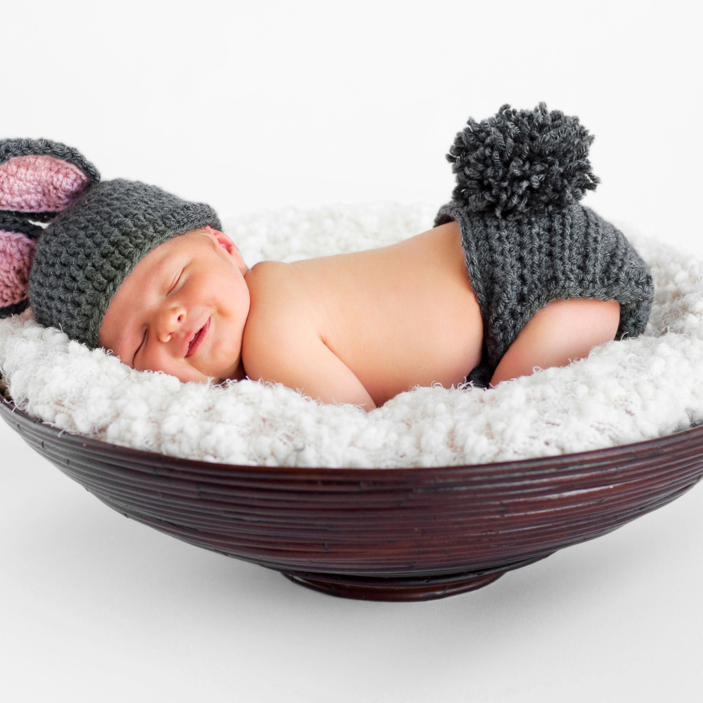 Маленький спящий грудной ребенок в вязаном костюме зайчика