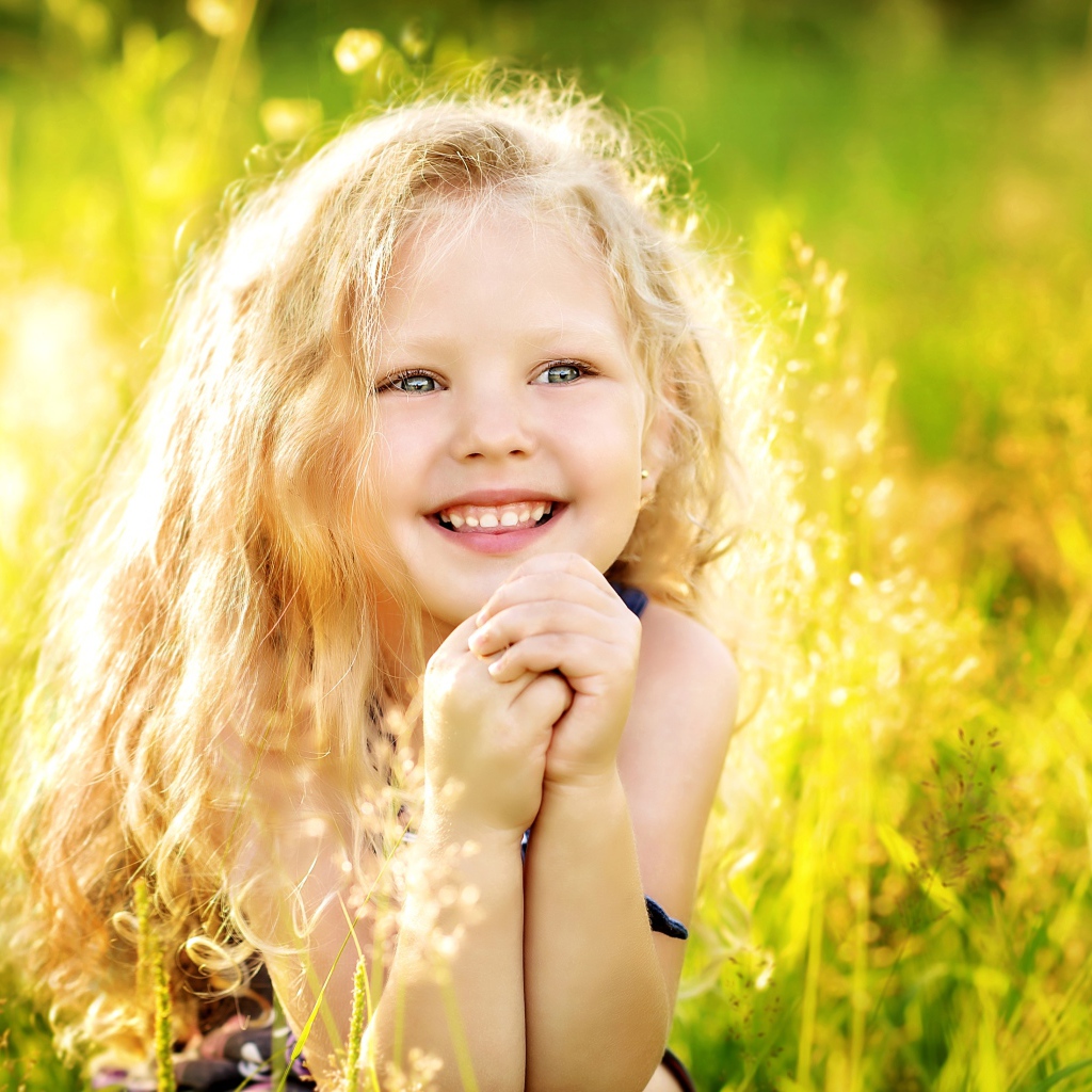 Маленькая улыбающаяся девочка в лучах солнца