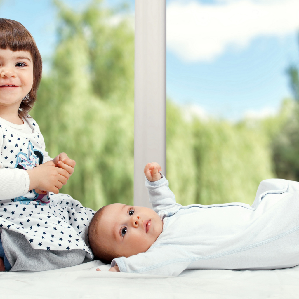 Маленькая улыбающаяся девочка с грудным ребенком