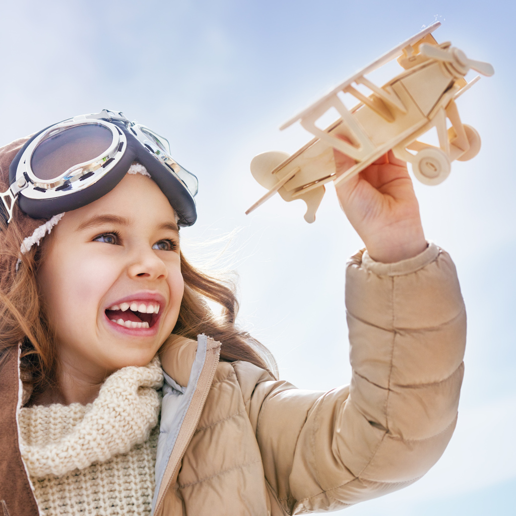 Маленькая улыбающаяся девочка с самолетом в руках 