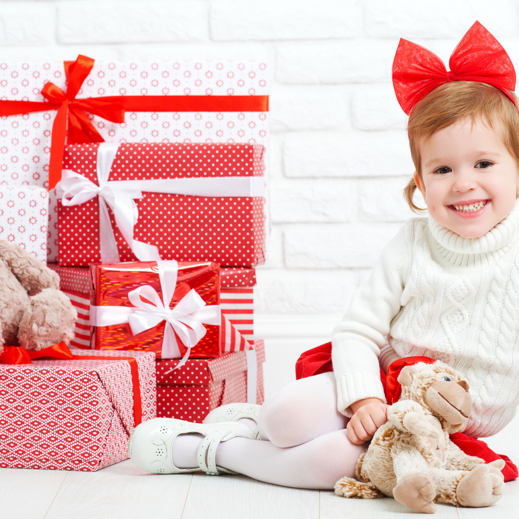 Маленькая улыбающаяся девочка с подарками на новый год