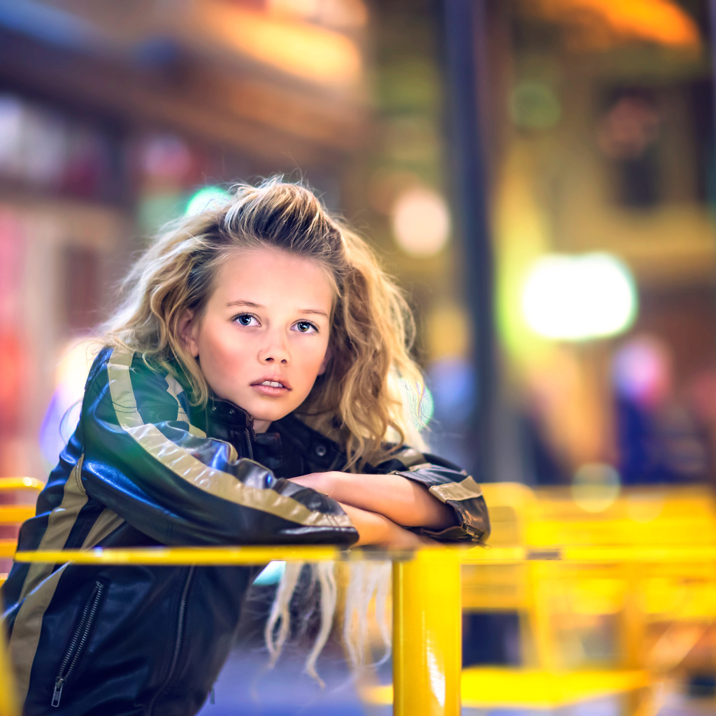 Длинноволосая девочка сидит на карусели