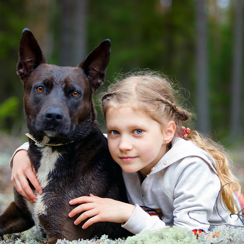 Милая голубоглазая девочка с большой черной собакой