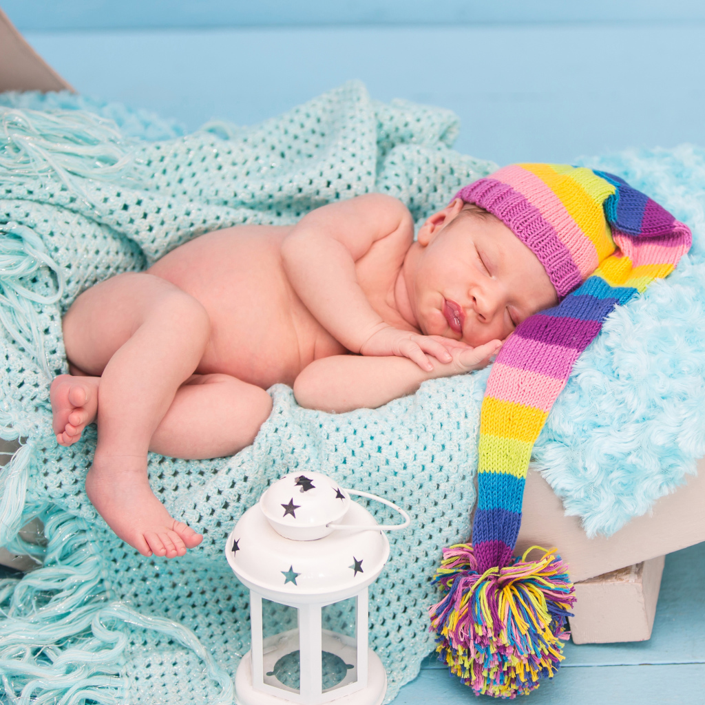 Спящий грудной ребенок в большой вязаной шапке