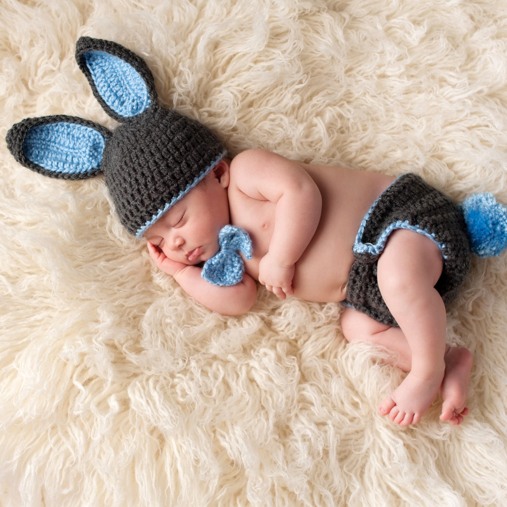 Спящий грудной ребенок в вязаном костюме кролика