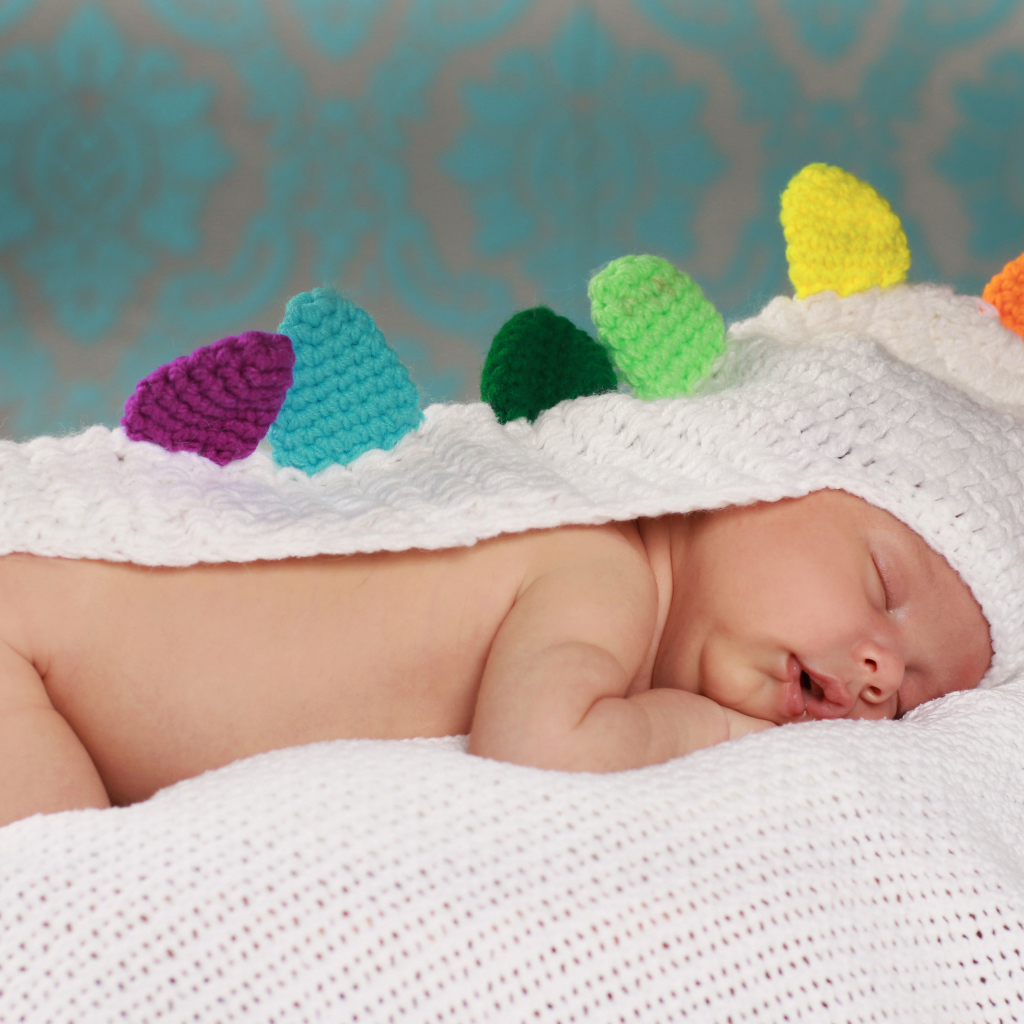 Спящий младенец в белой вязаной накидке