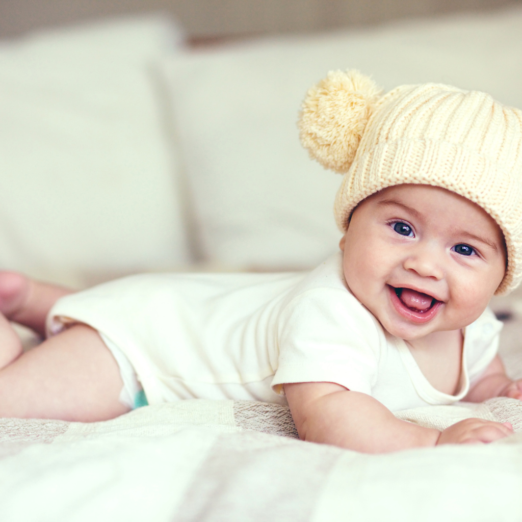 Улыбающийся грудной ребенок в забавной вязаной шапке