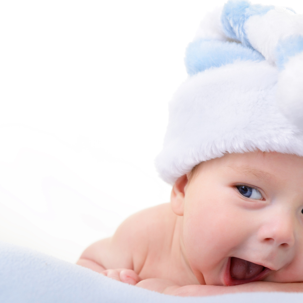 Улыбающийся грудной ребенок в голубой новогодней шапке