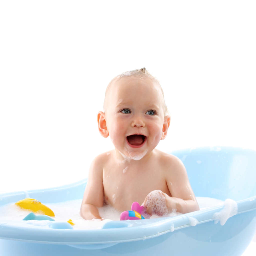 Улыбающийся грудной ребенок сидит в синей ванночке на белом фоне
