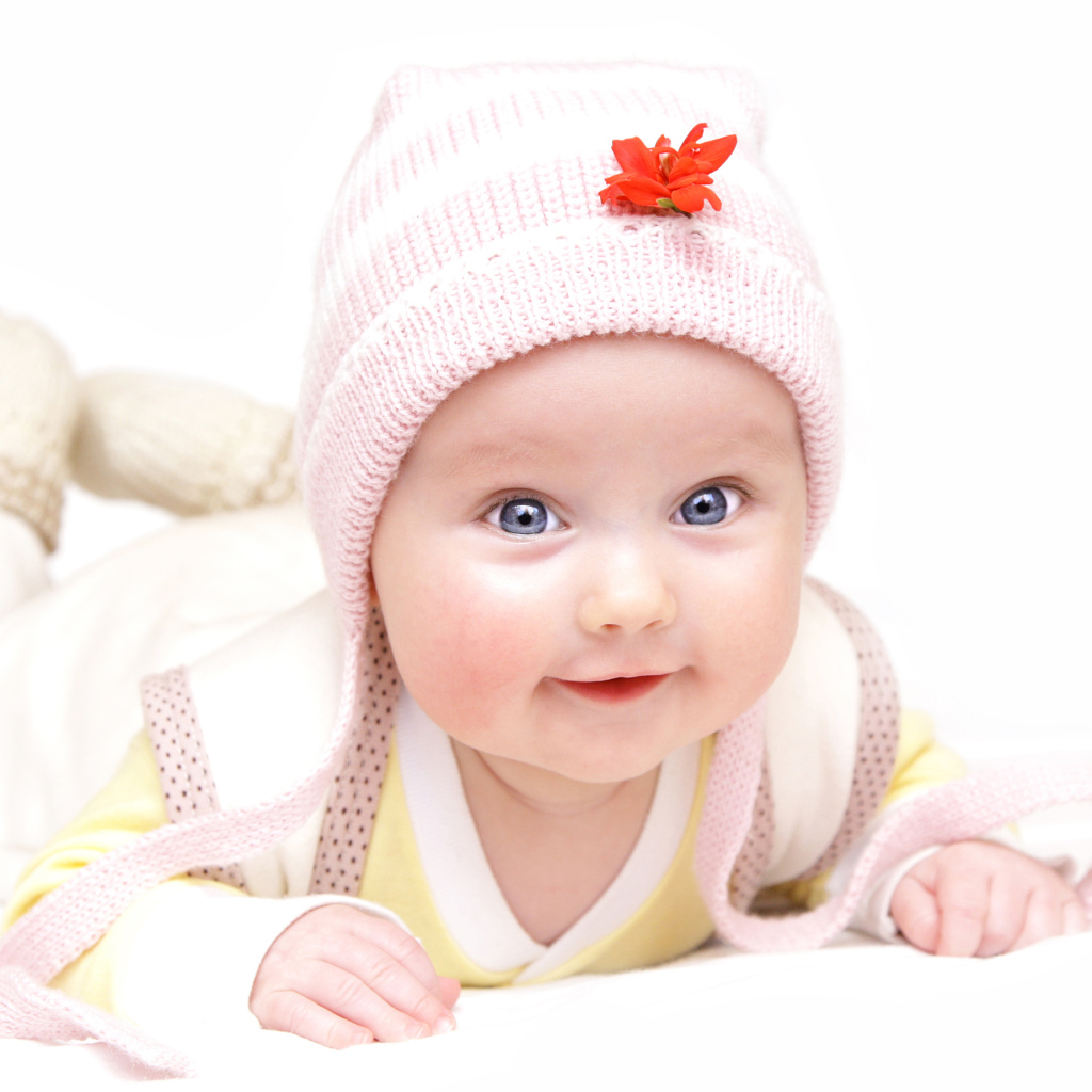 Улыбающийся голубоглазый малыш в розовой шапке