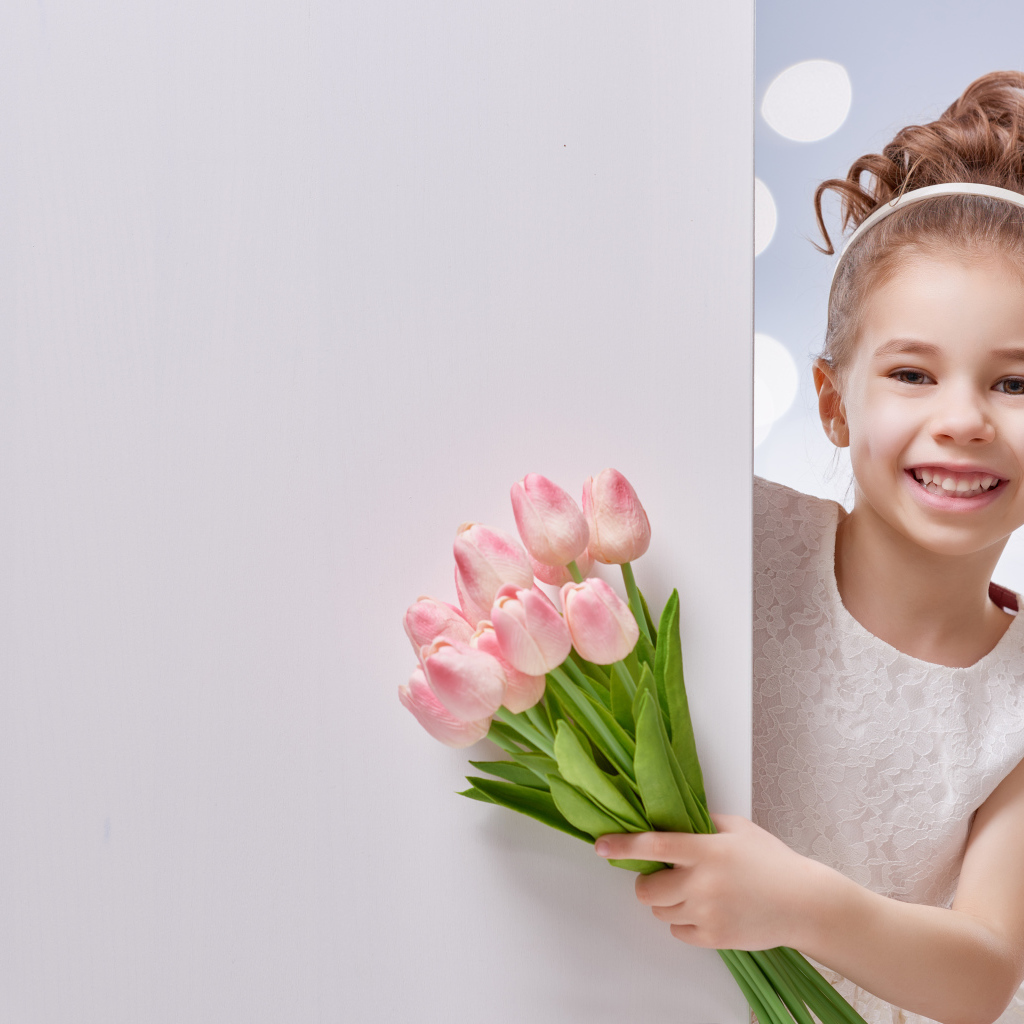Улыбающаяся маленькая девочка с букетом розовых тюльпанов