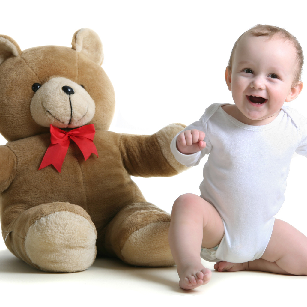 Улыбающийся малыш с большим плюшевым медведем на белом фоне