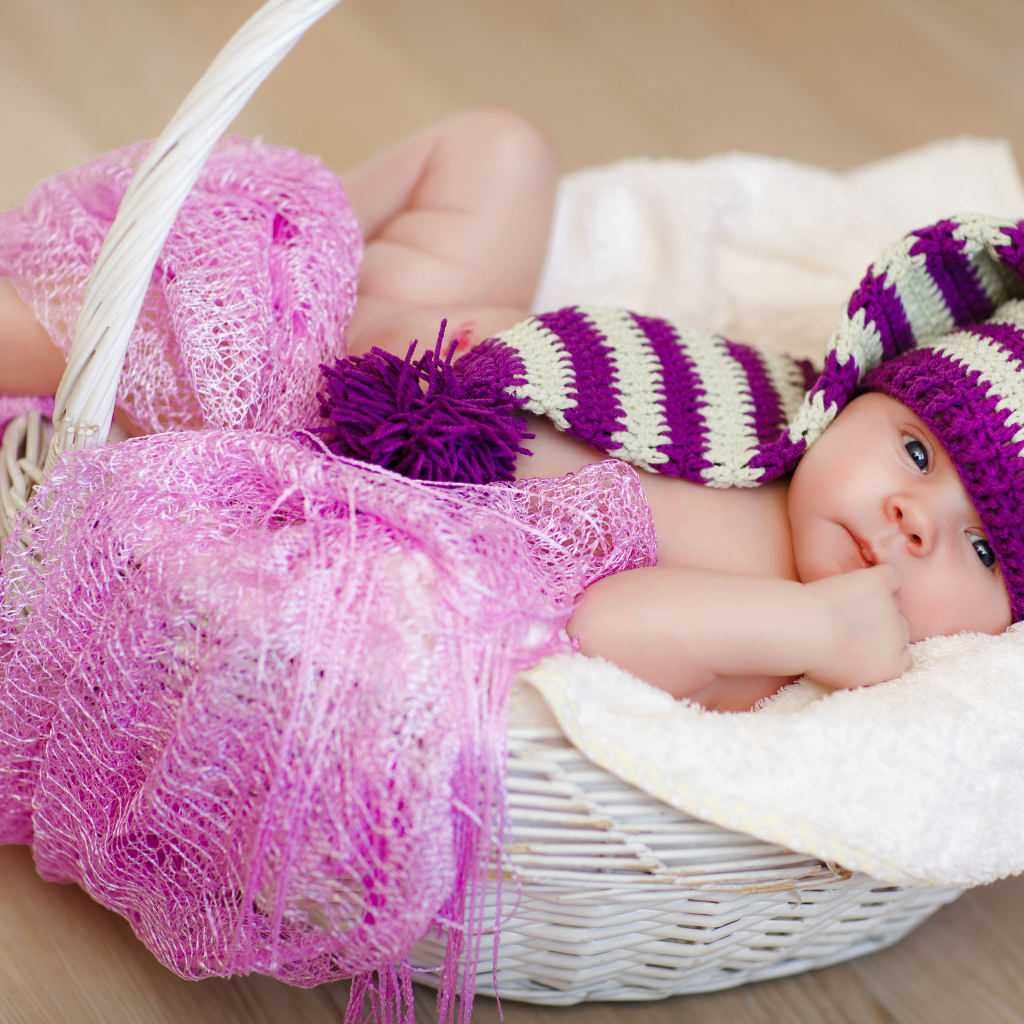 Младенец в красивой вязаной шапке лежит в корзине