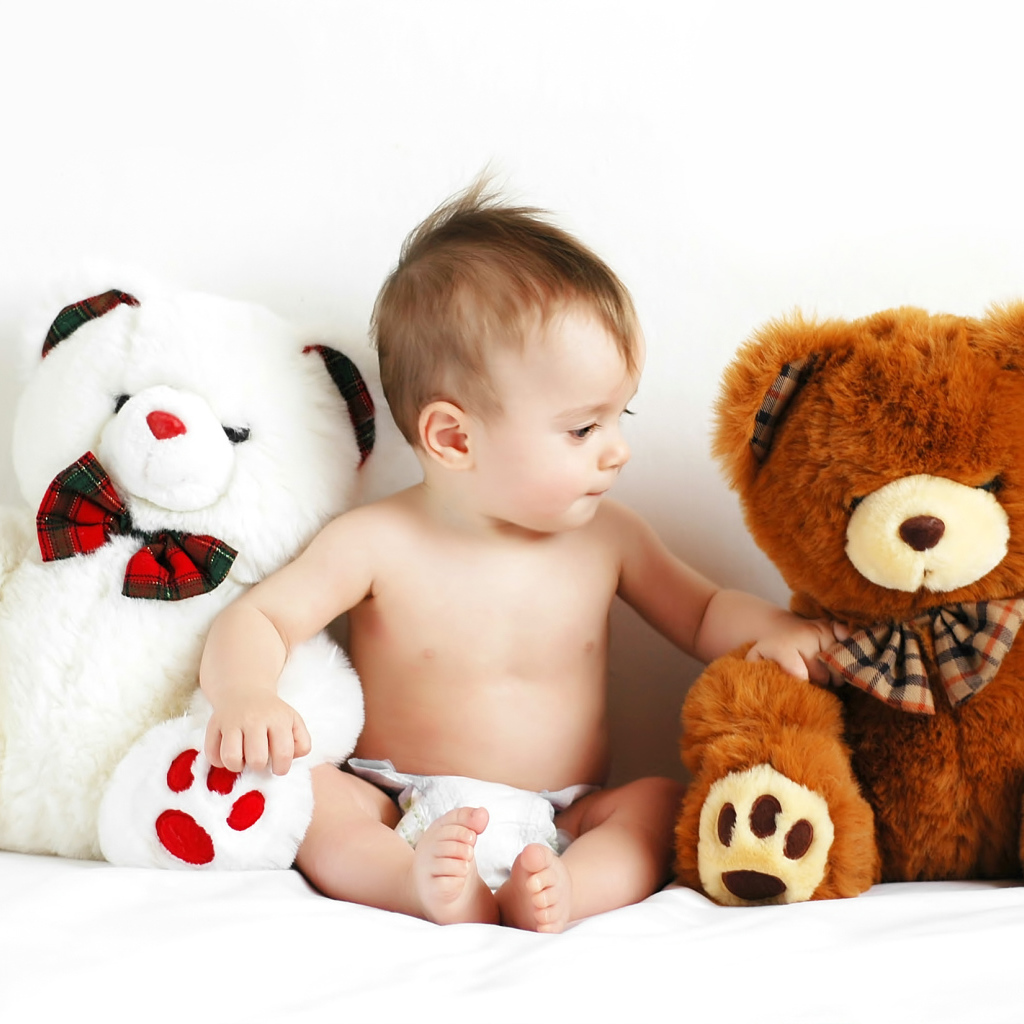 Младенец сидит с двумя большими плюшевыми медведями