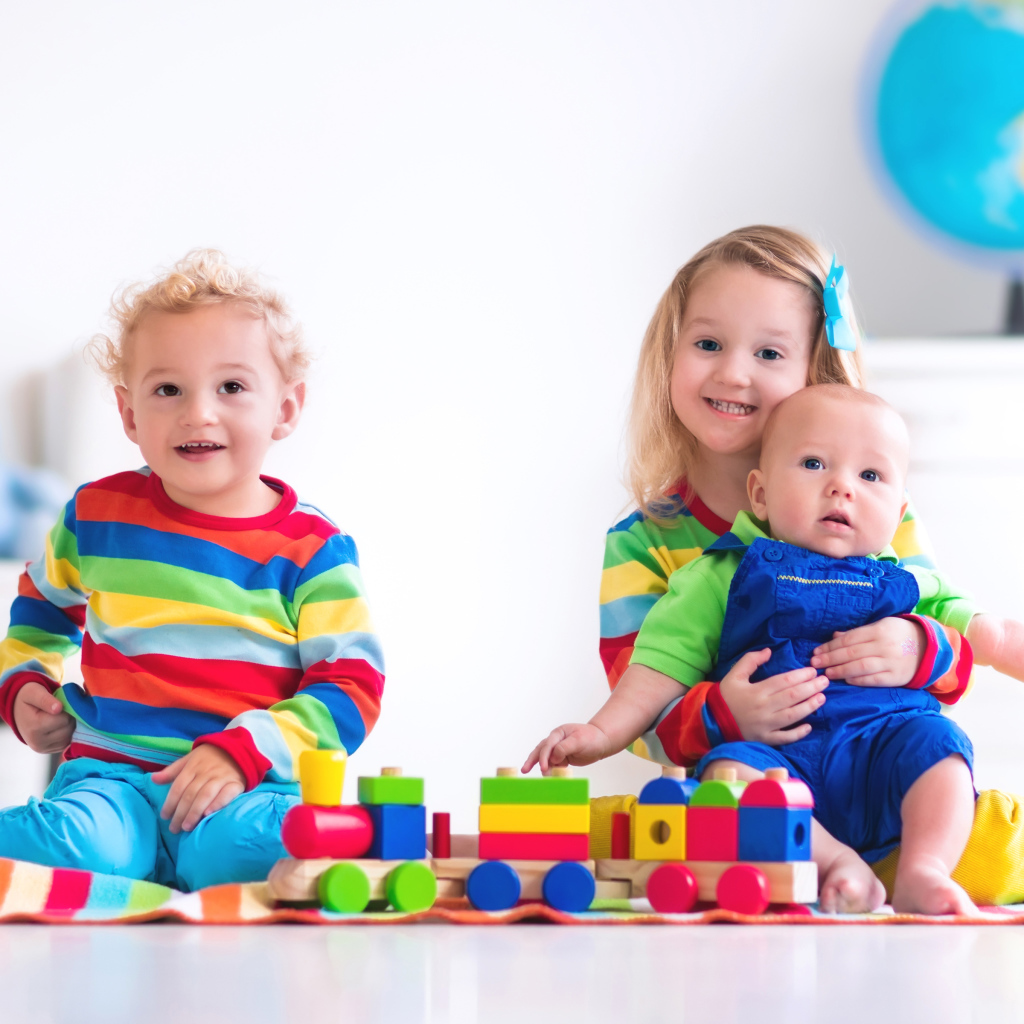 Три ребенка играют с игрушечным поездом