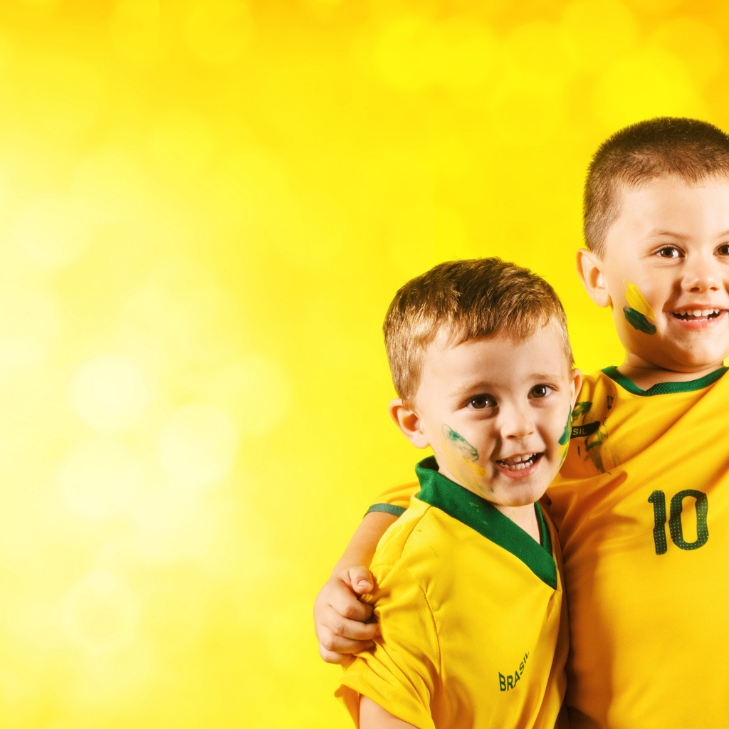 Два маленьких мальчика в спортивной форме на желтом фоне