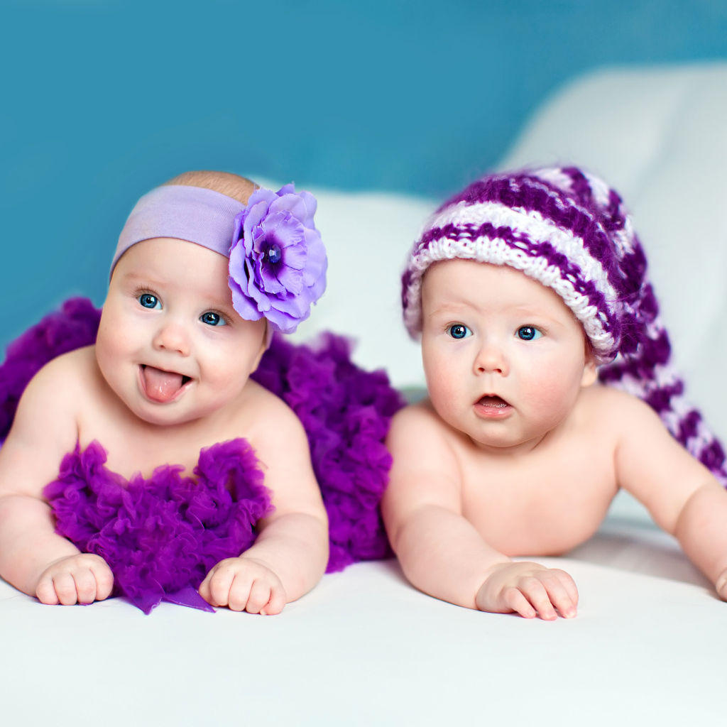 Два маленьких забавных младенца в красивых фиолетовых костюмах