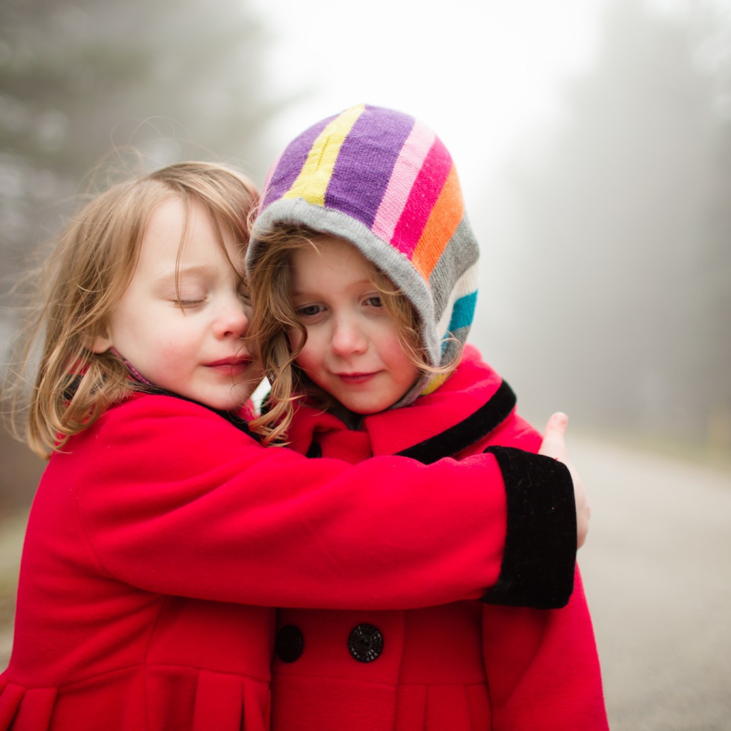 Две маленькие девочки обнимают друг друга 