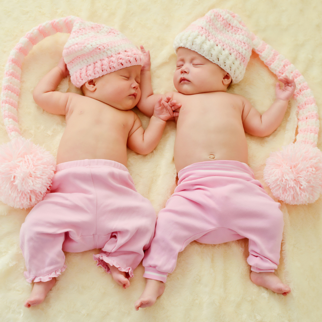Два спящих грудных ребенка в розовых костюмах