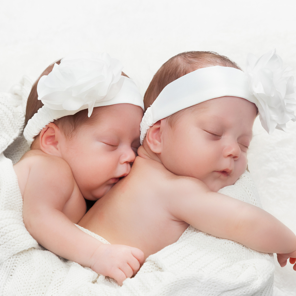 Два спящих младенца с большими белыми цветами на голове
