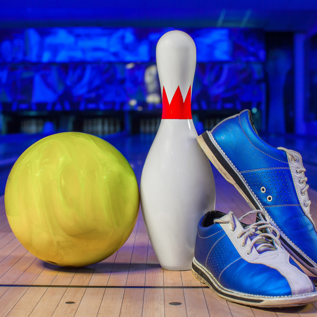 Синие кроссовки, шар и кегля на дорожке для боулинга
