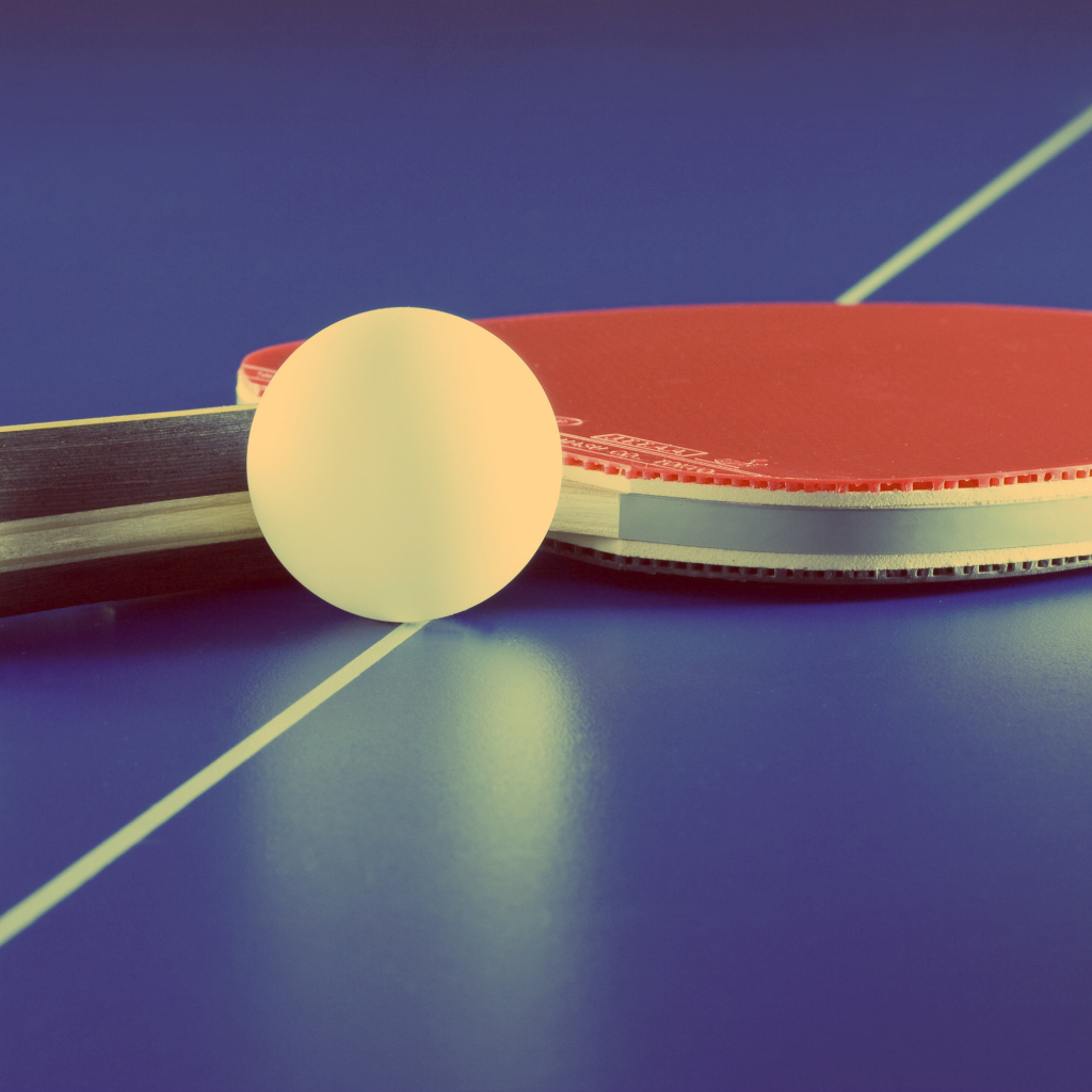 Ракетка для настольного тенниса и мяч на фиолетовом столе 
