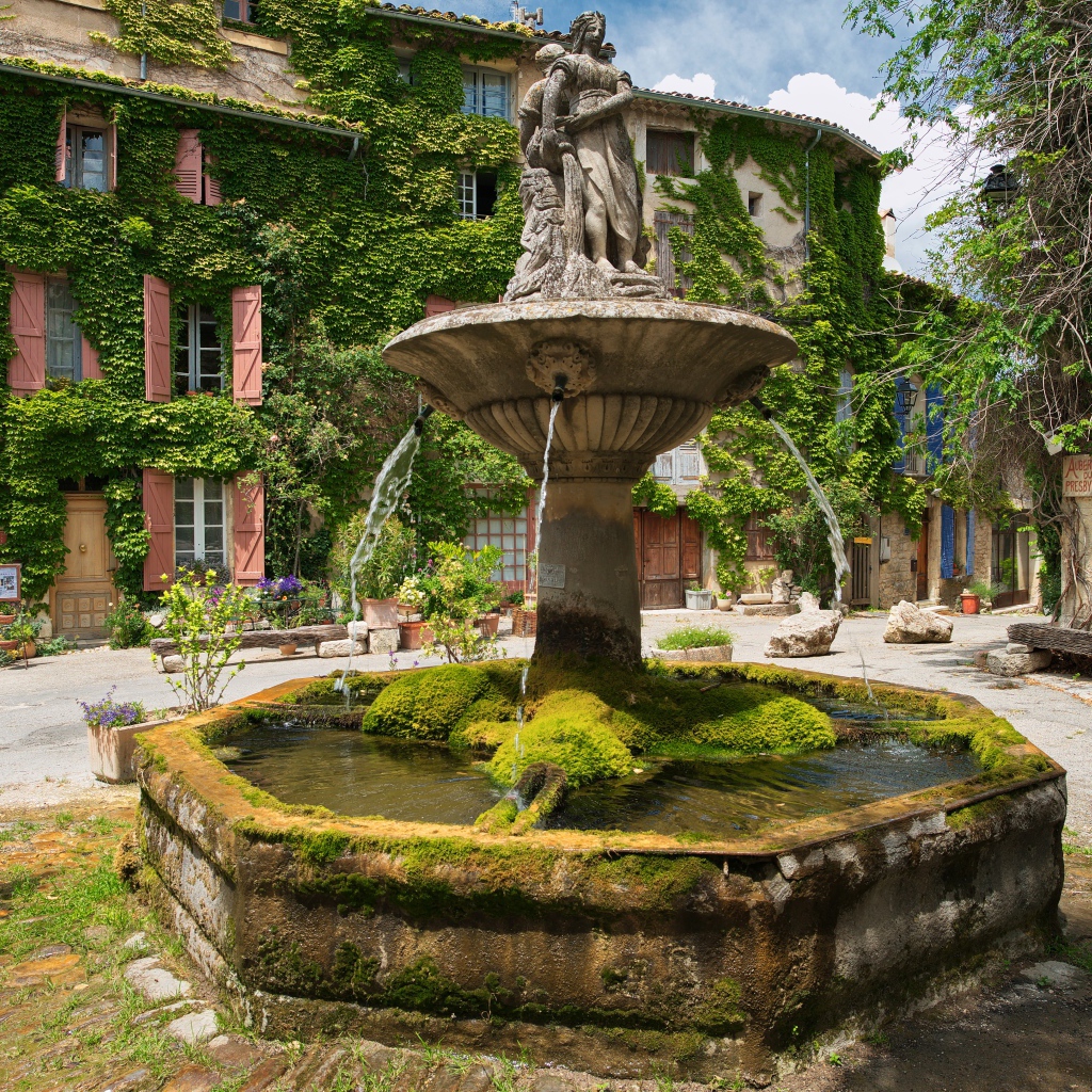 Старинный покрытый мхом фонтан на площади Сеньон, Франция