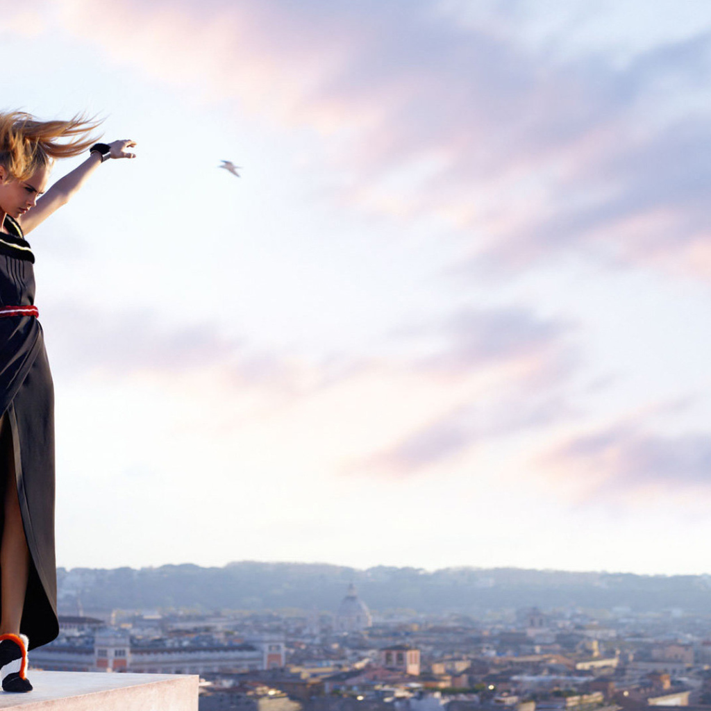 Актриса Кара Делевинь в черном платье на фоне неба 