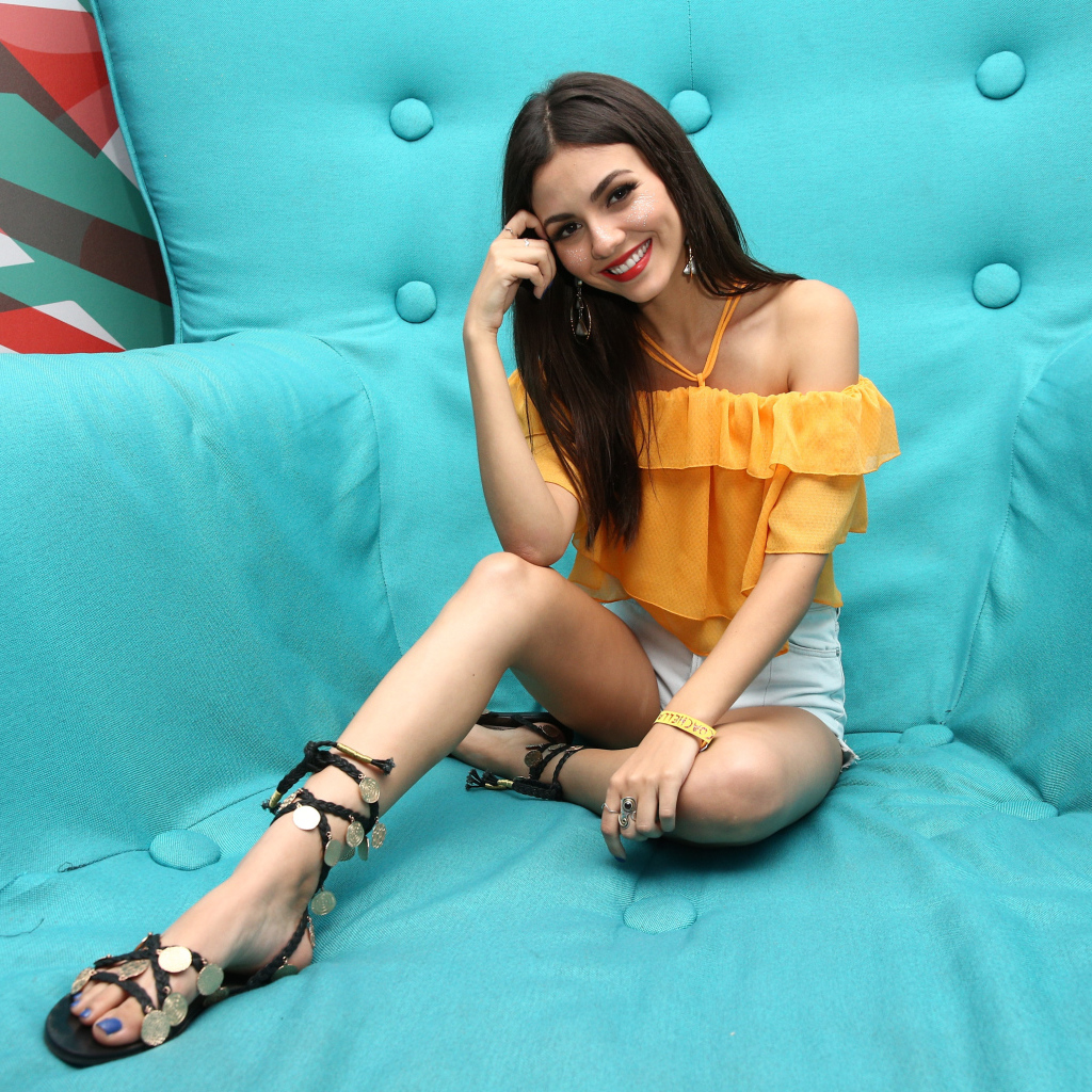 Актриса брюнетка Виктория Джастис сидит на синем диване 