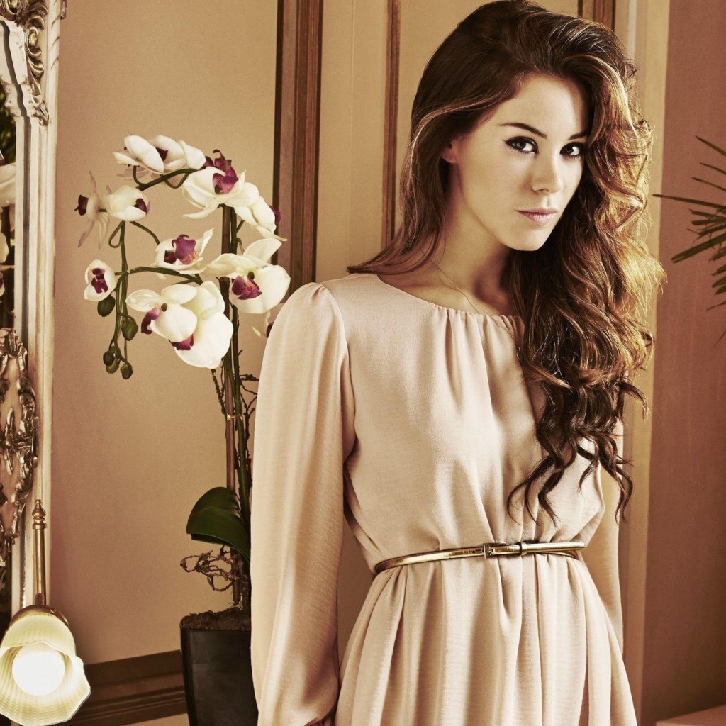 Брюнетка актриса Роксанна Макки стоит рядом с цветком орхидеи