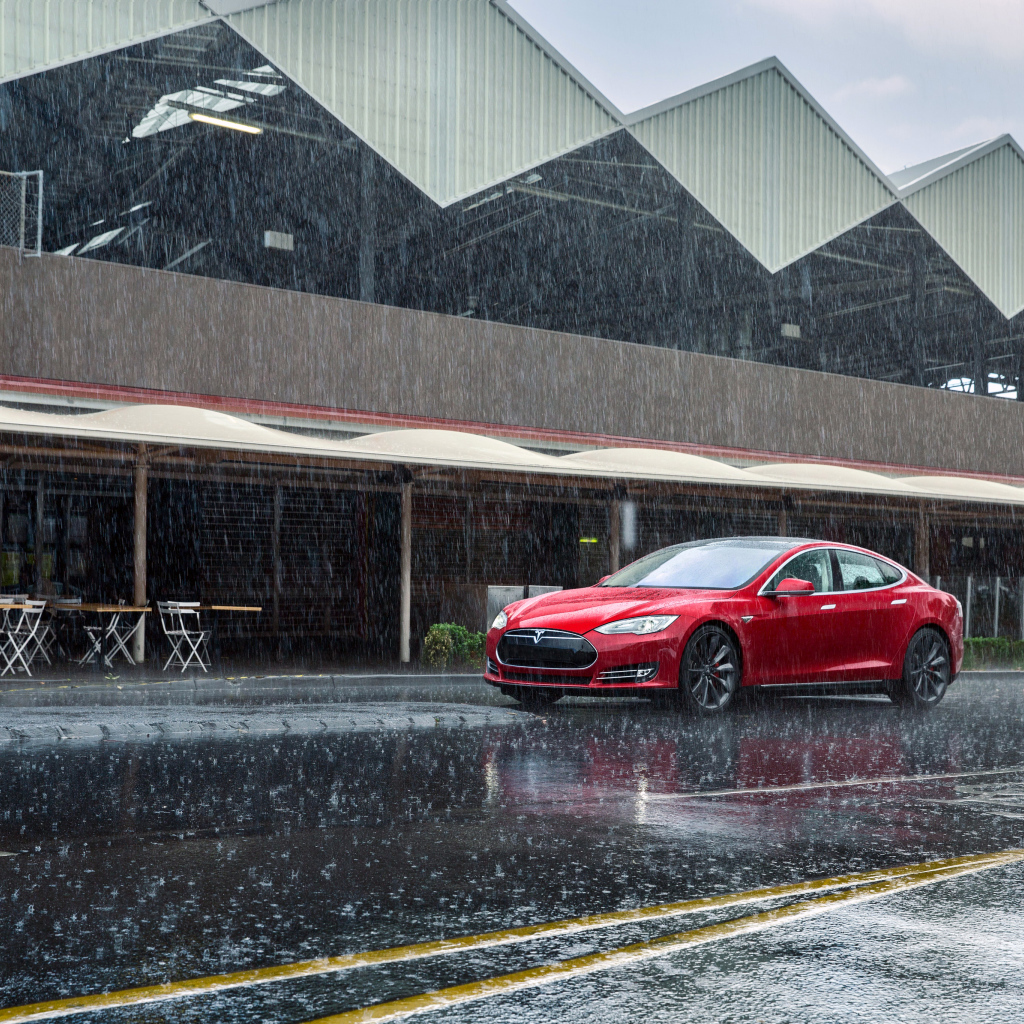 Красный автомобиль  Tesla Model S на дороге под дождем