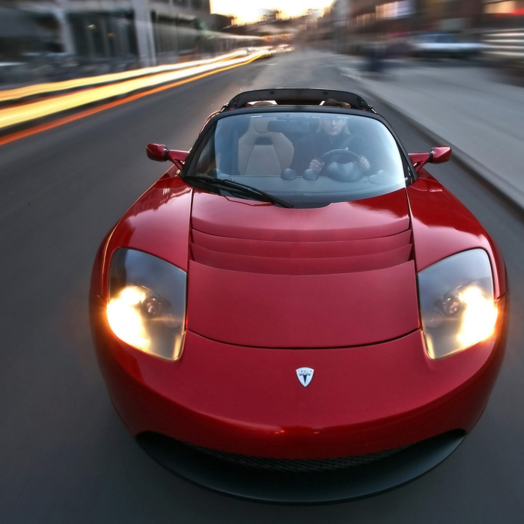 Красный электромобиль Tesla Roadster на трассе 