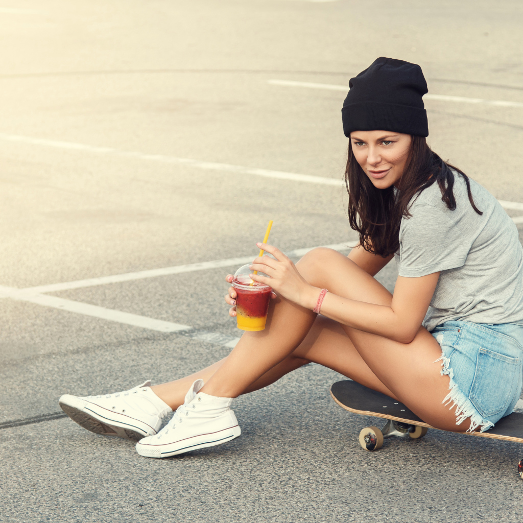 Спортивная девушка сидит на доске для скейтборда 