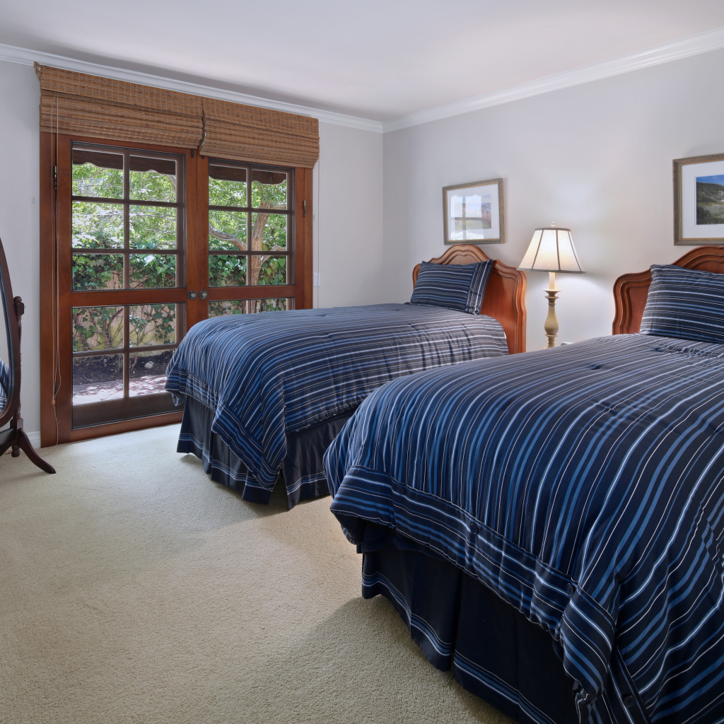 Две большие кровати в спальне с деревянным окном