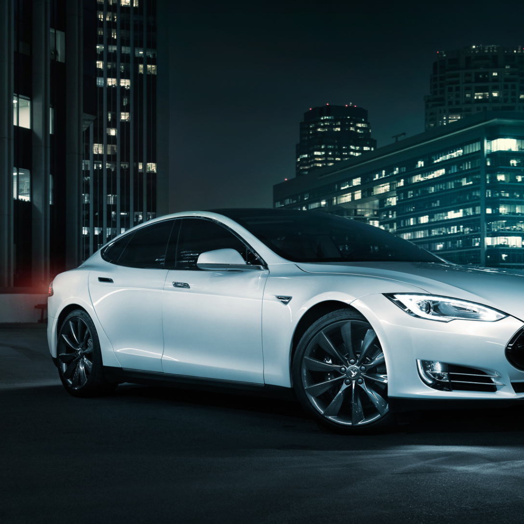 Белый электромобиль Тесла на фоне города 