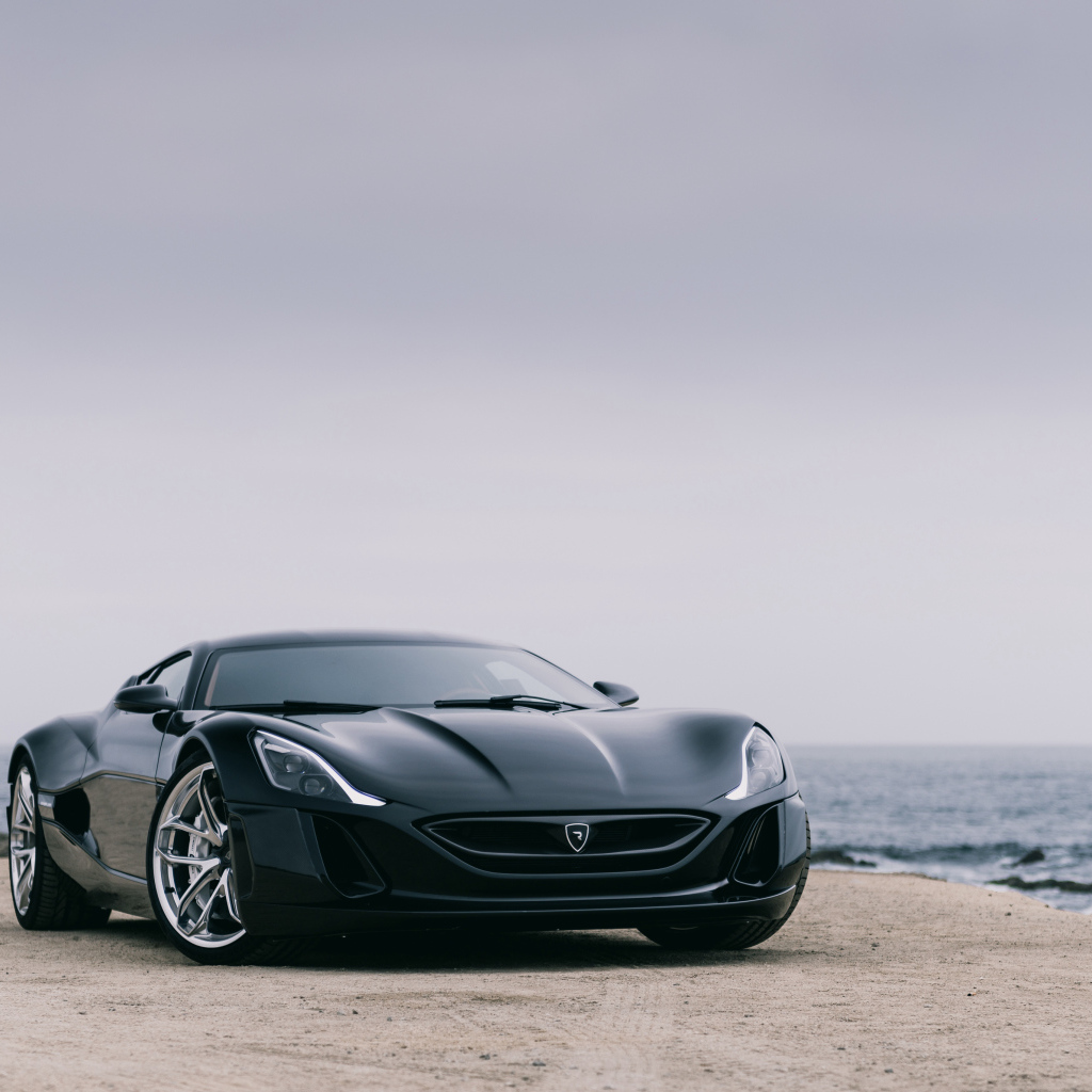Черный спортивный автомобиль Rimac Concept One на фоне океана