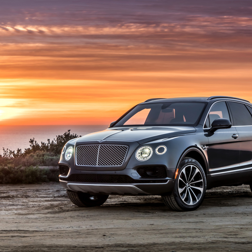 Черный стильный стильный автомобиль Bentley на фоне заката 