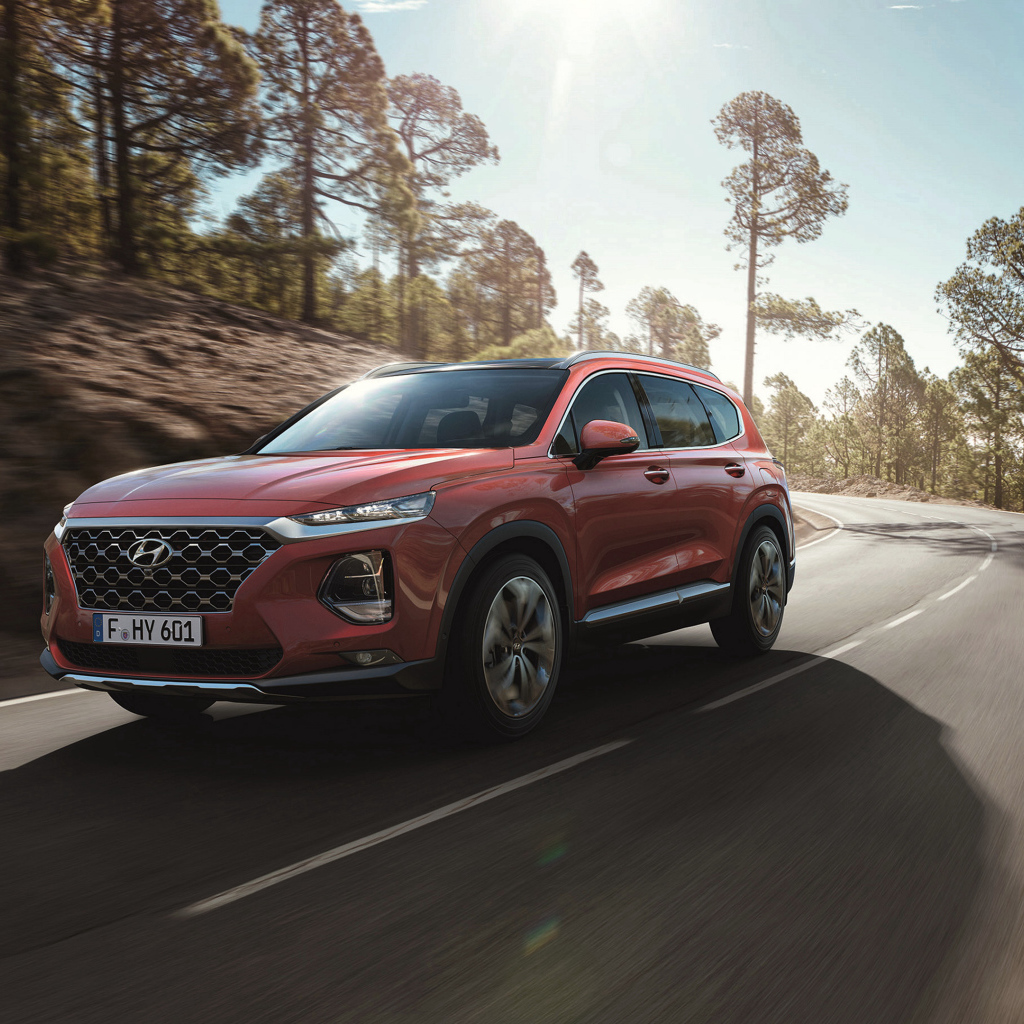 Красный автомобиль Hyundai Santa Fe, 2018 года на трассе