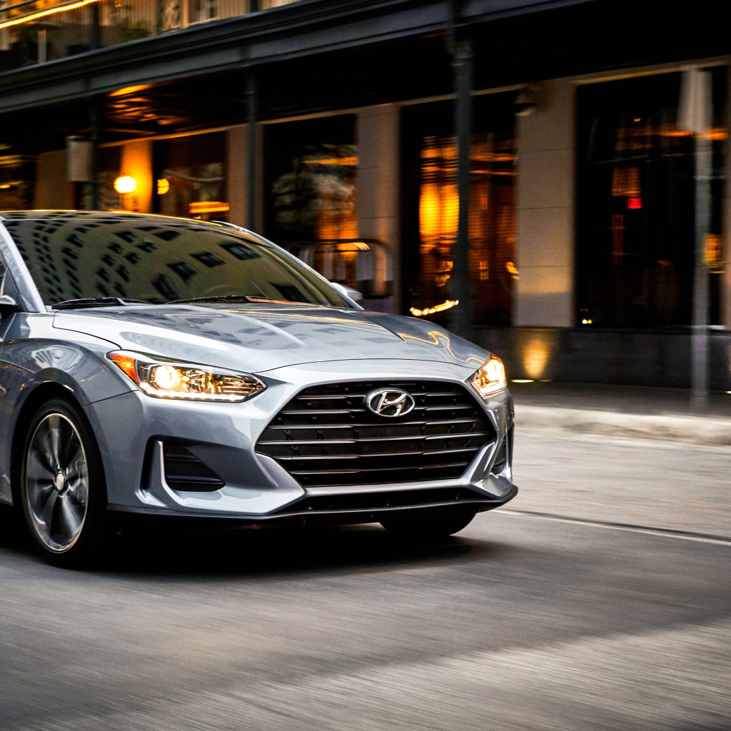 Серебристый автомобиль Hyundai Veloster, 2019 с  включенными фарами 